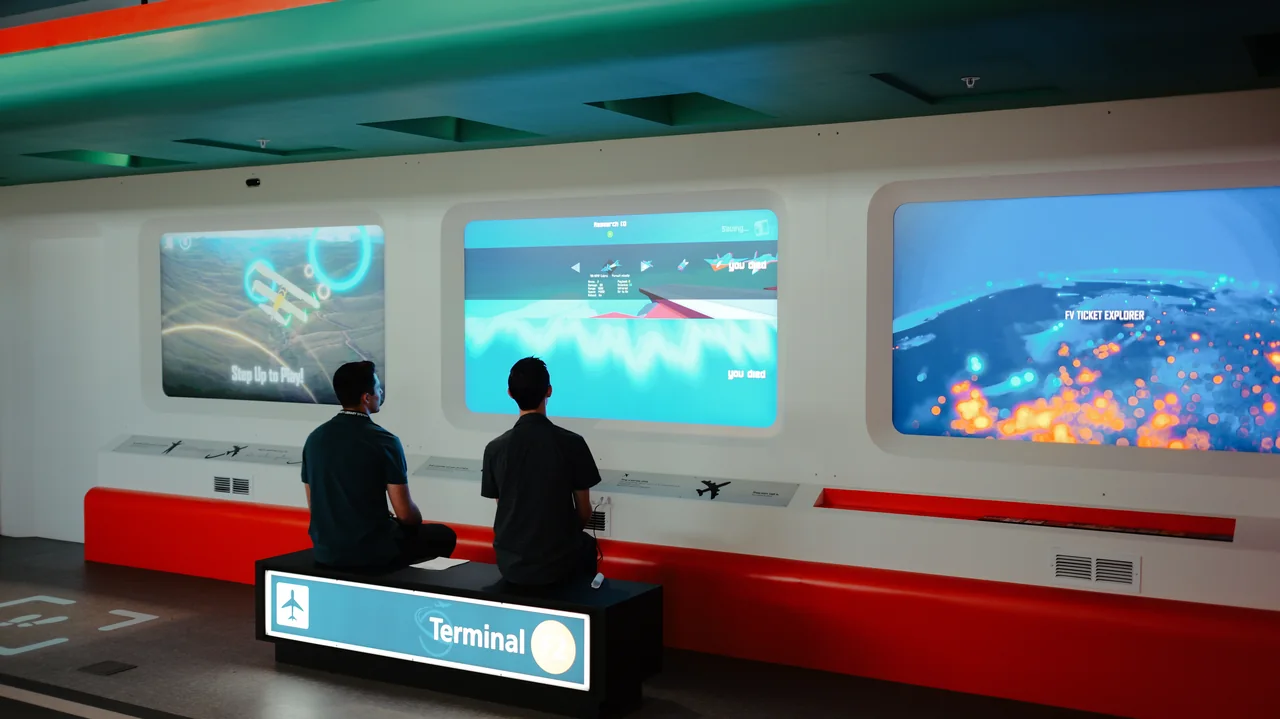 Visitors facing three large aviation media screens.