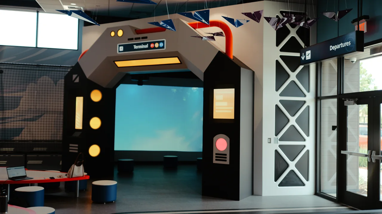 A flight simulator screen is set within a sculptural white and orange surround.