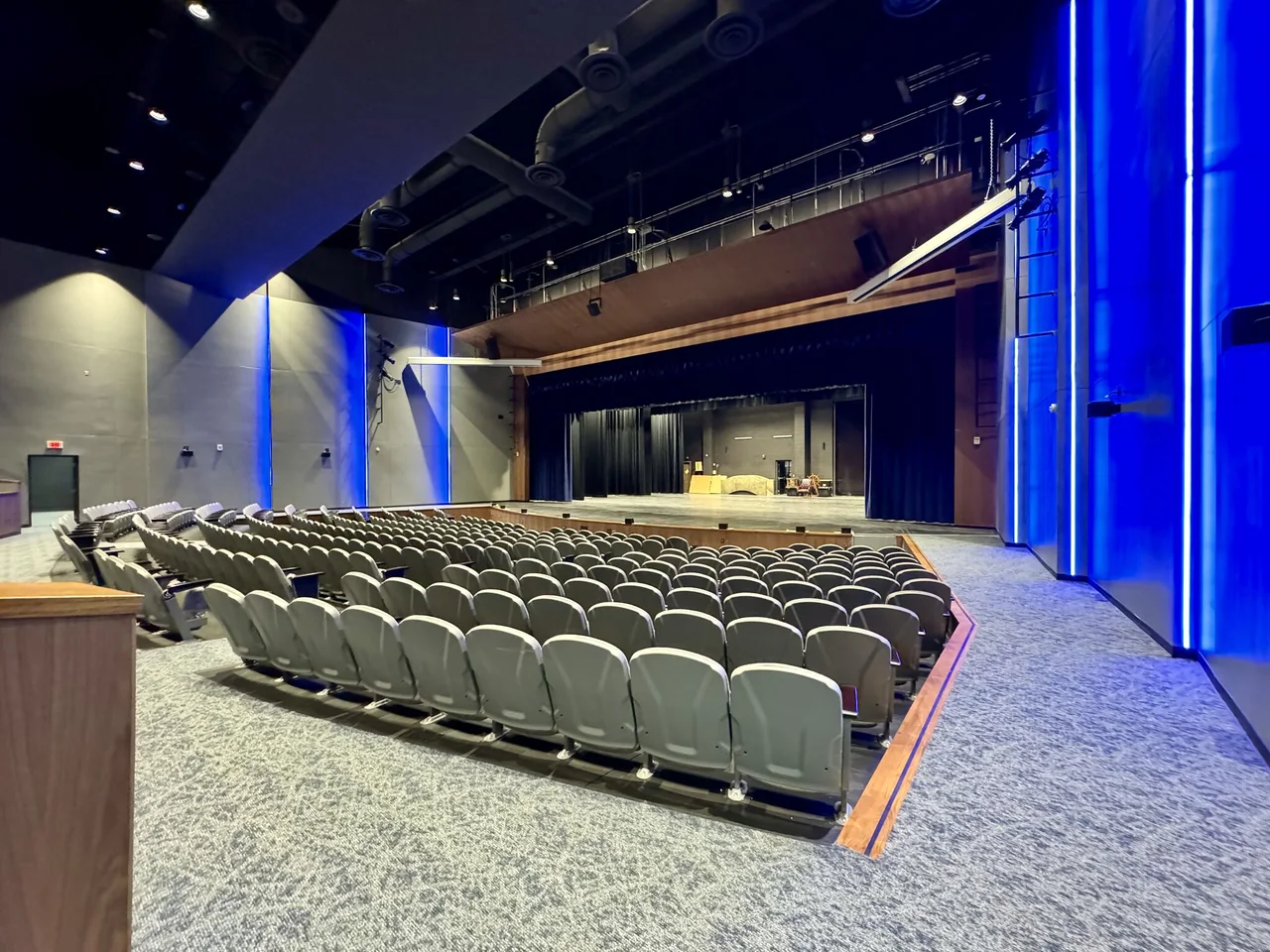 Rows of auditorium seats face a stage framed in blue.