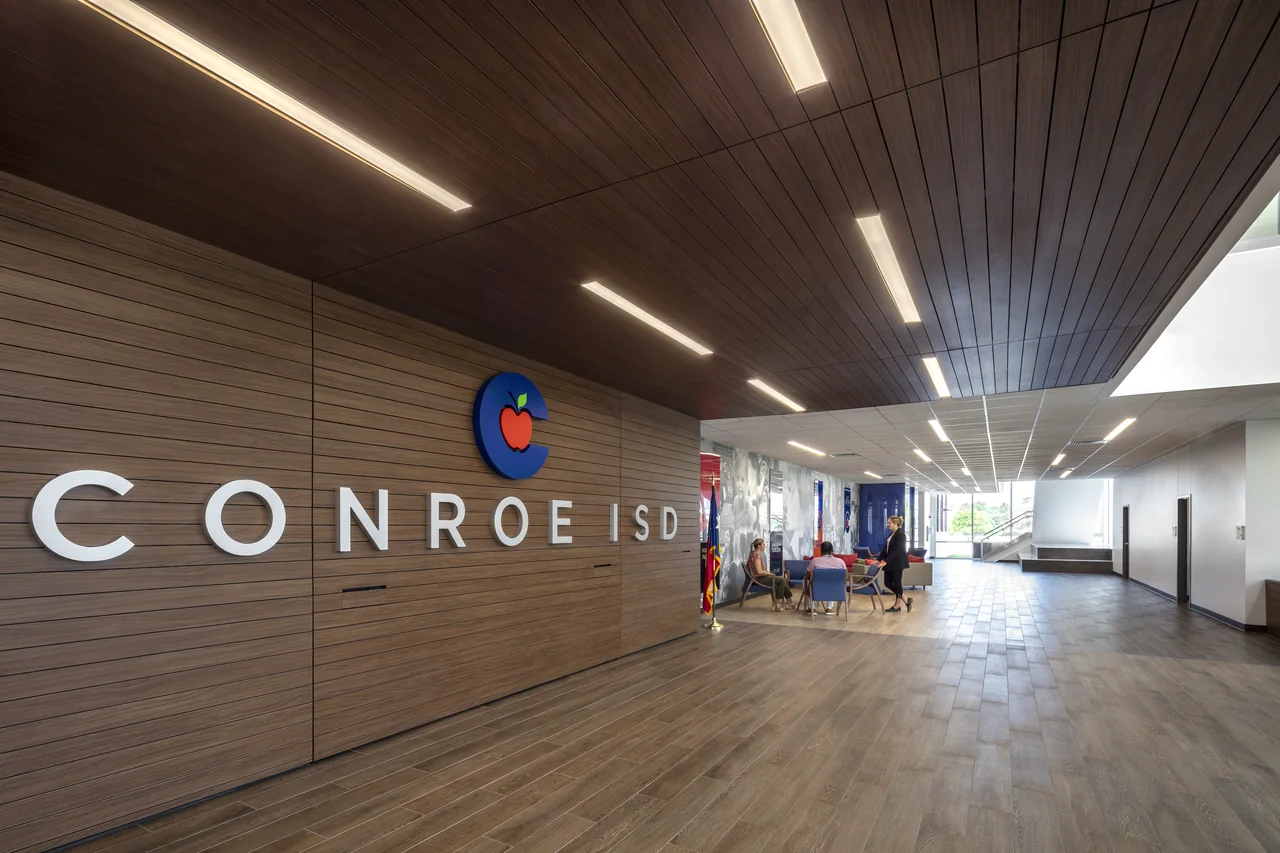 Timber walls and illuminated ceiling lines lead through the Conroe ISD lobby.