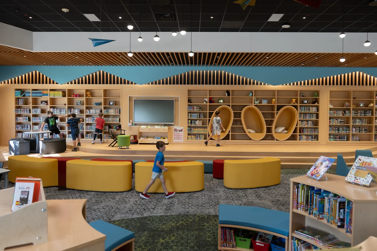 Completed school library with varied seating, timber shelves, circular niches and a presentation area.