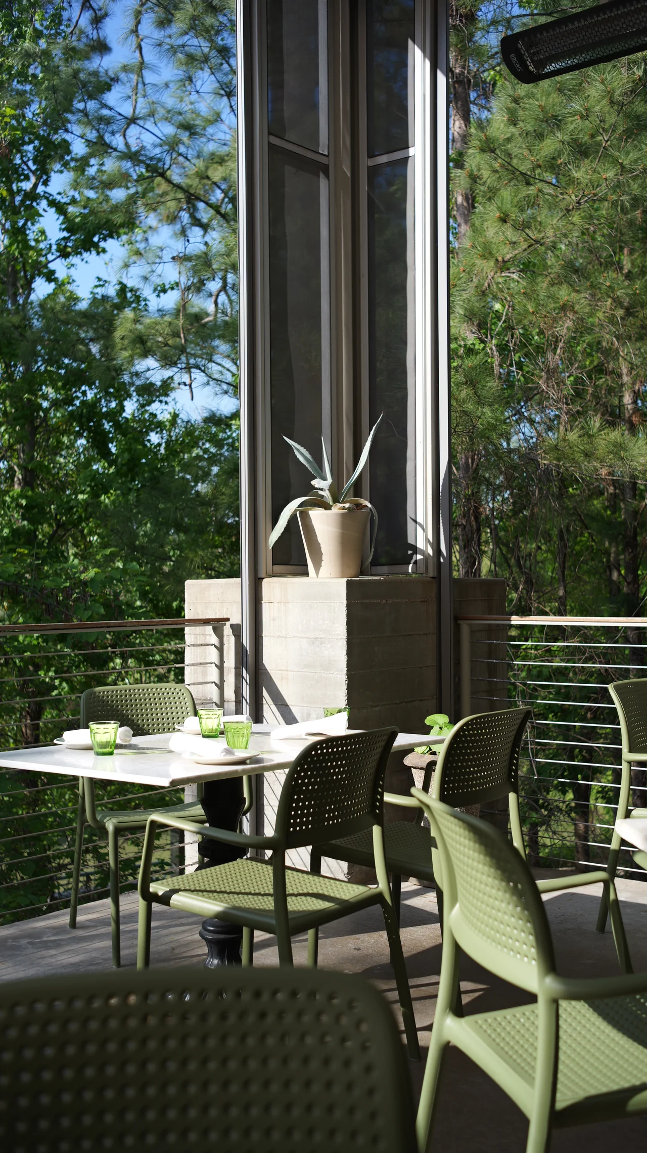 Daylight illuminates a table and chairs beside tall windows.