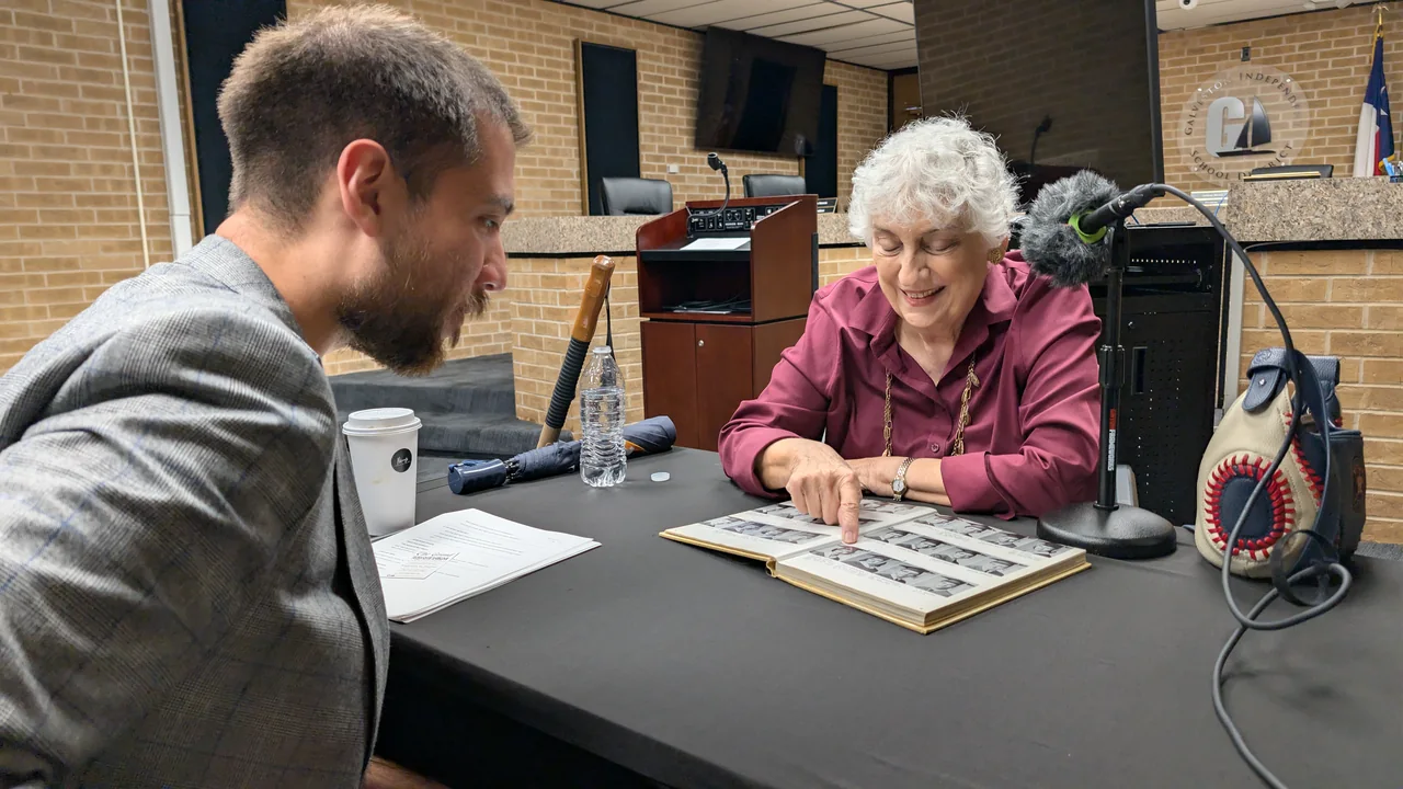 An interview participant sharing photographs across a table with Michael Zepeda.